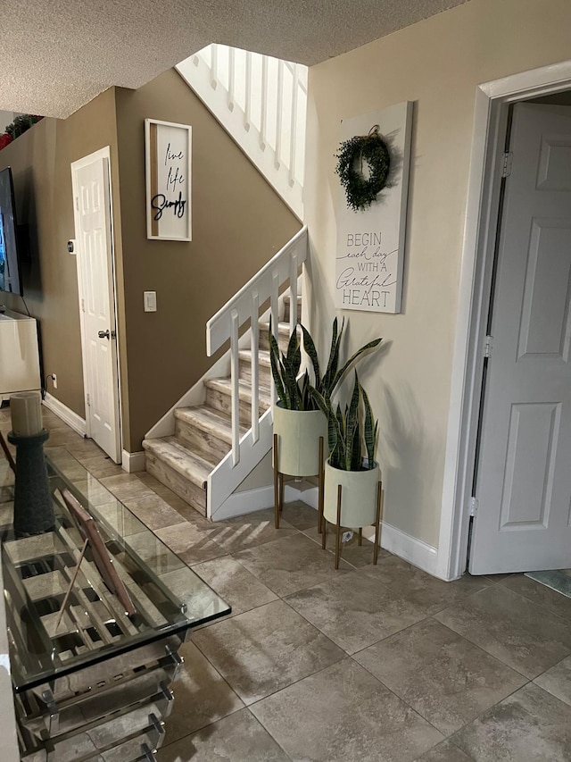 staircase featuring a textured ceiling