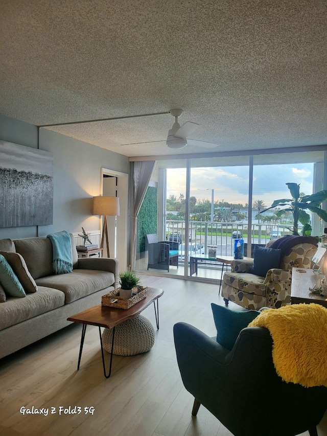 living room featuring a textured ceiling, light hardwood / wood-style flooring, and ceiling fan