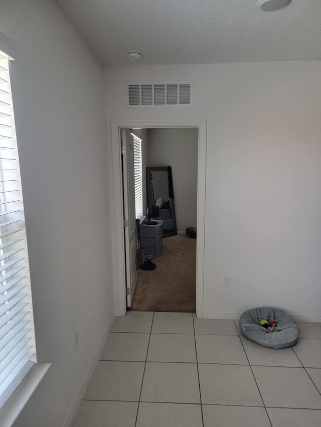 hallway featuring light tile patterned floors and plenty of natural light