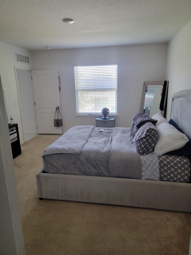 bedroom featuring light colored carpet and a textured ceiling