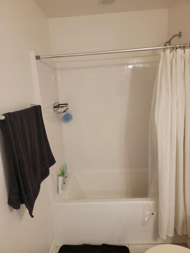 bathroom featuring toilet and shower / tub combo with curtain