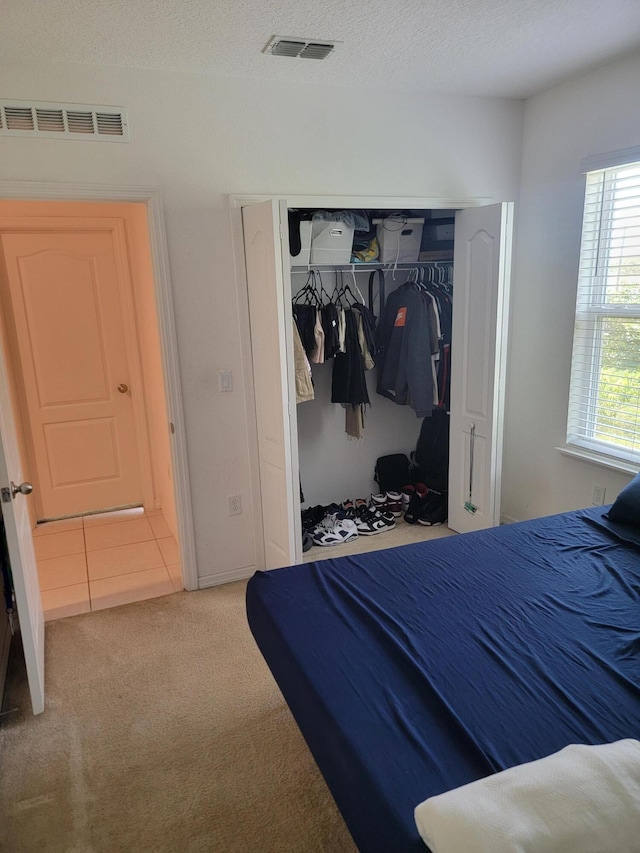 bedroom with a closet, carpet, and a textured ceiling