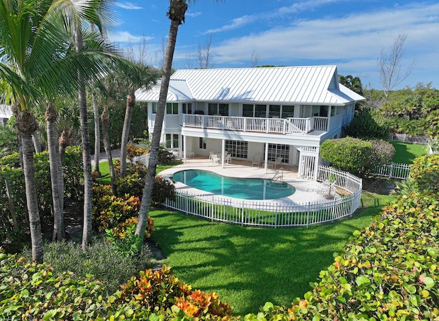 back of property featuring a lawn, a balcony, a patio area, and a fenced in pool