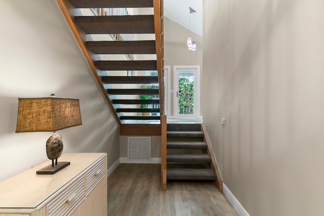 stairway featuring high vaulted ceiling and hardwood / wood-style floors