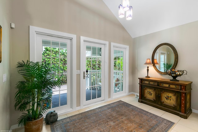 doorway with a wealth of natural light, an inviting chandelier, high vaulted ceiling, and light tile patterned floors