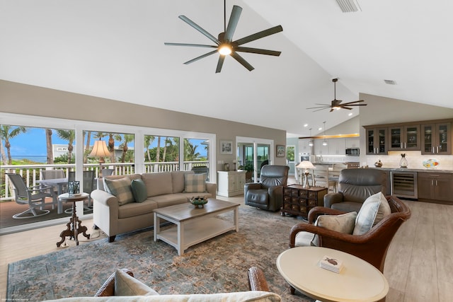 living room featuring wine cooler, high vaulted ceiling, light wood-type flooring, and ceiling fan