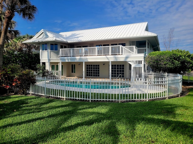 back of house with a fenced in pool, a yard, a patio, and a balcony