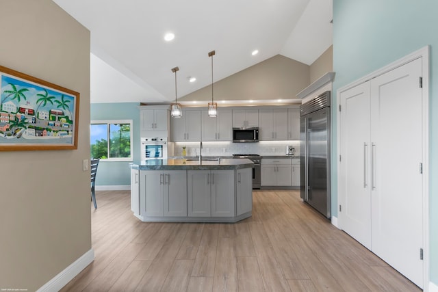 kitchen with gray cabinetry, sink, an island with sink, hanging light fixtures, and high end appliances