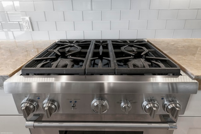 interior details with decorative backsplash, light stone countertops, and stainless steel range oven