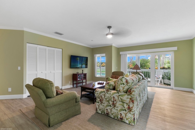 living room with light hardwood / wood-style floors, crown molding, and a wealth of natural light