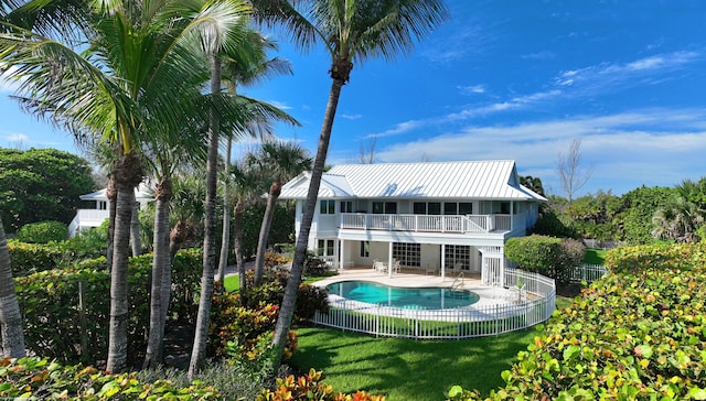 back of house featuring a fenced in pool, a patio, a lawn, and a balcony