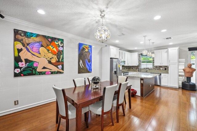 dining room with crown molding, a healthy amount of sunlight, and light hardwood / wood-style flooring