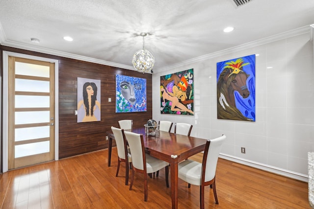 dining space with a notable chandelier, hardwood / wood-style flooring, and crown molding