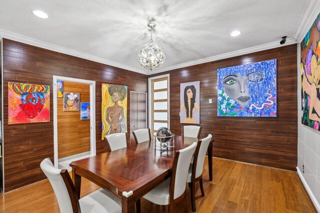 dining area featuring wood walls, hardwood / wood-style flooring, crown molding, and a textured ceiling