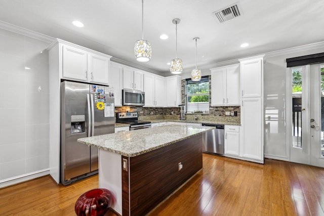 kitchen featuring appliances with stainless steel finishes, white cabinetry, hardwood / wood-style floors, pendant lighting, and ornamental molding