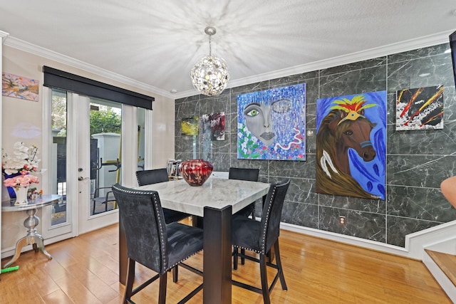 dining room with crown molding, wood finished floors, a chandelier, and tile walls