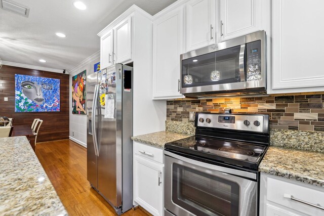 kitchen with stainless steel appliances, ornamental molding, and white cabinets