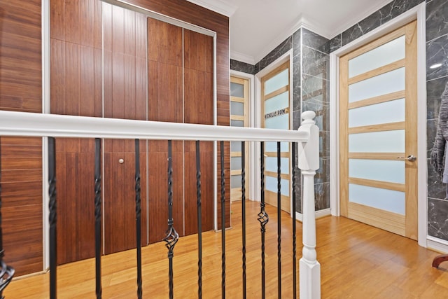 staircase with wood finished floors and crown molding