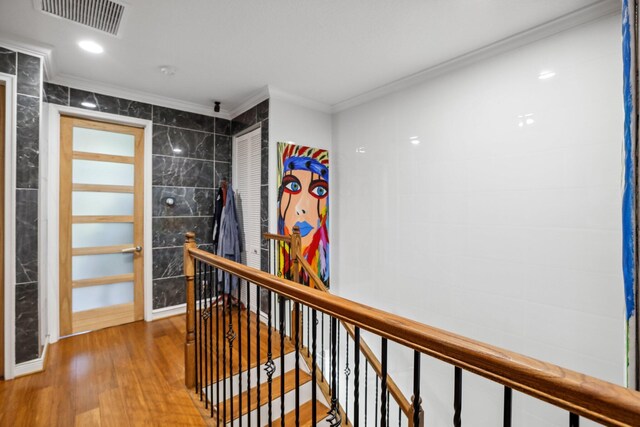 corridor featuring tile walls, ornamental molding, and wood-type flooring