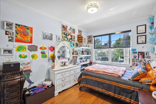 bedroom with ornamental molding, a textured ceiling, and wood finished floors
