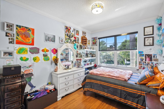 bedroom with hardwood / wood-style flooring, crown molding, and a textured ceiling