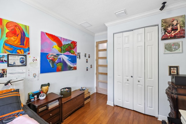 bedroom with a textured ceiling, ornamental molding, a closet, and hardwood / wood-style flooring