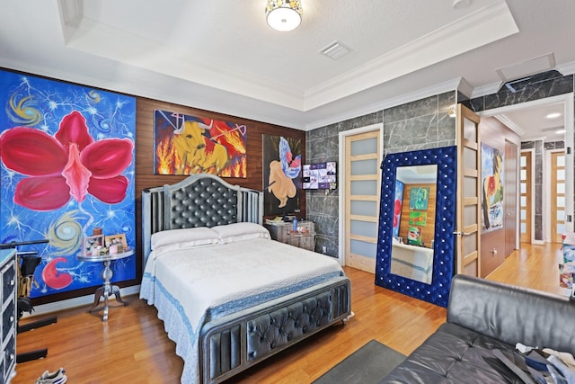 bedroom featuring a tray ceiling, crown molding, and wood finished floors