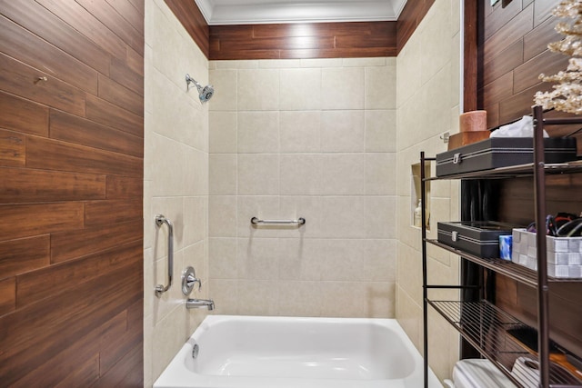 bathroom with tiled shower / bath combo, toilet, and wooden walls