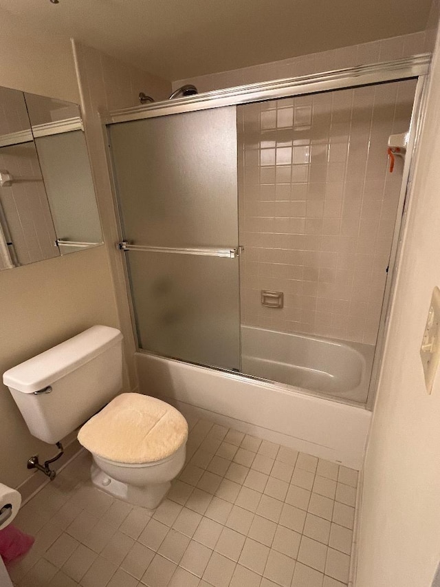 bathroom featuring tile patterned flooring, toilet, and combined bath / shower with glass door