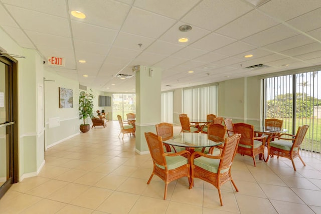 dining space featuring a paneled ceiling and light tile patterned flooring