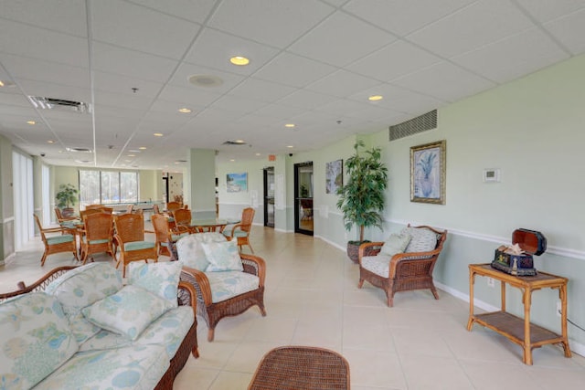 living room featuring a drop ceiling and light tile patterned flooring