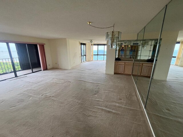 unfurnished living room featuring a textured ceiling, plenty of natural light, and carpet