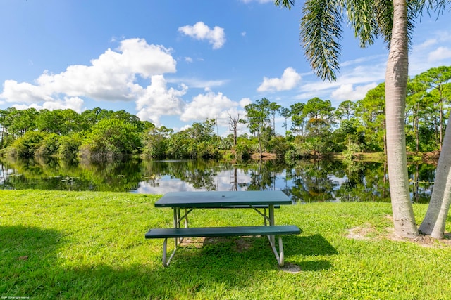 surrounding community with a water view and a lawn