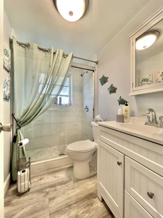 full bath with vanity, a stall shower, wood finished floors, and toilet