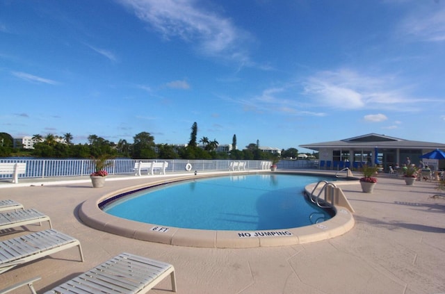 pool with a patio area and fence