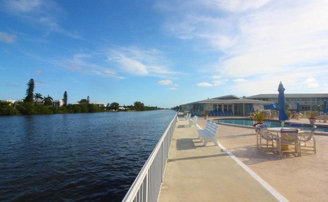 dock area featuring a patio, a water view, and a community pool