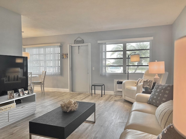 living room with a wall mounted air conditioner, wood finished floors, and baseboards