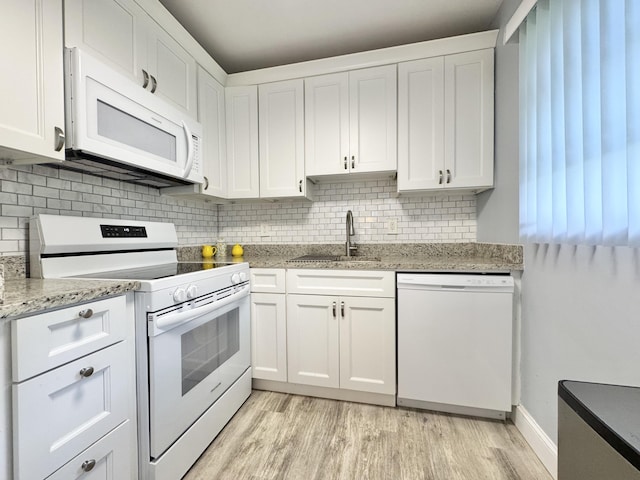 kitchen featuring tasteful backsplash, light wood-style flooring, white cabinetry, a sink, and white appliances