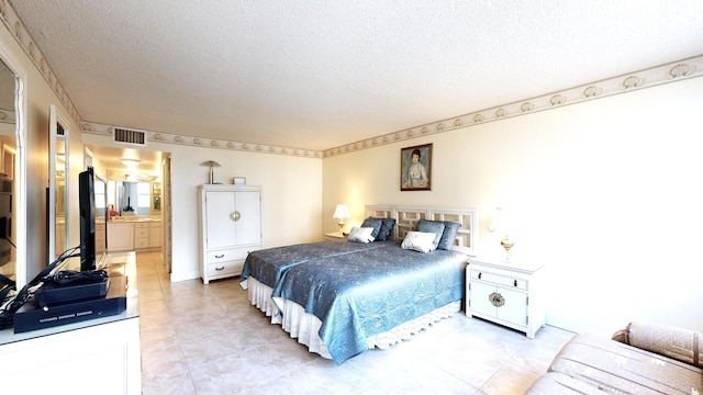 bedroom featuring a textured ceiling, connected bathroom, and light tile patterned floors