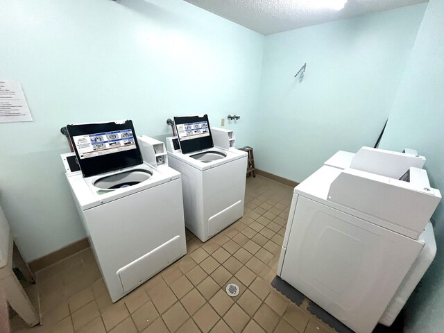 washroom featuring a textured ceiling, light tile patterned floors, and washer and dryer