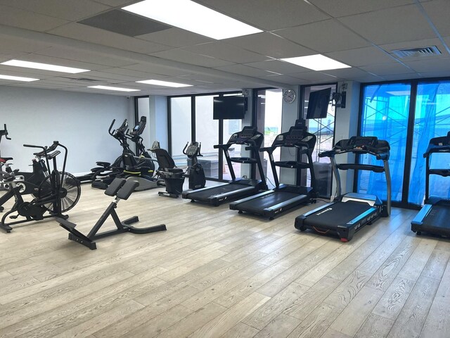 exercise room with light hardwood / wood-style flooring and a paneled ceiling