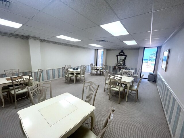 carpeted dining room featuring a drop ceiling