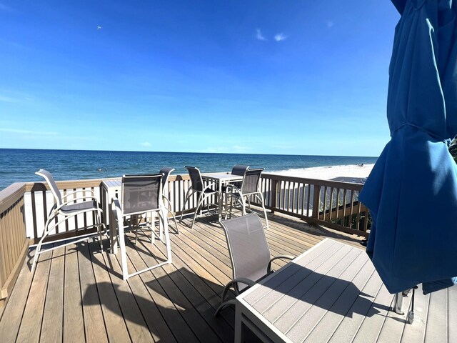wooden deck featuring a water view and a beach view