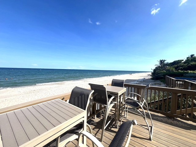 wooden deck with a water view and a view of the beach