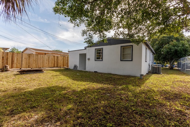 rear view of house with central AC and a yard