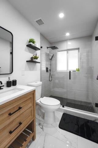 bathroom with vanity, toilet, and a shower with door