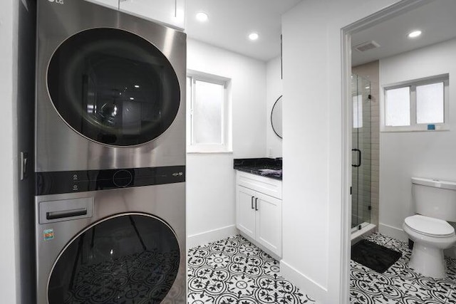 clothes washing area featuring stacked washer and clothes dryer and light tile patterned flooring