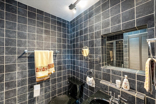 bathroom featuring a textured ceiling, decorative backsplash, a tile shower, and tile walls