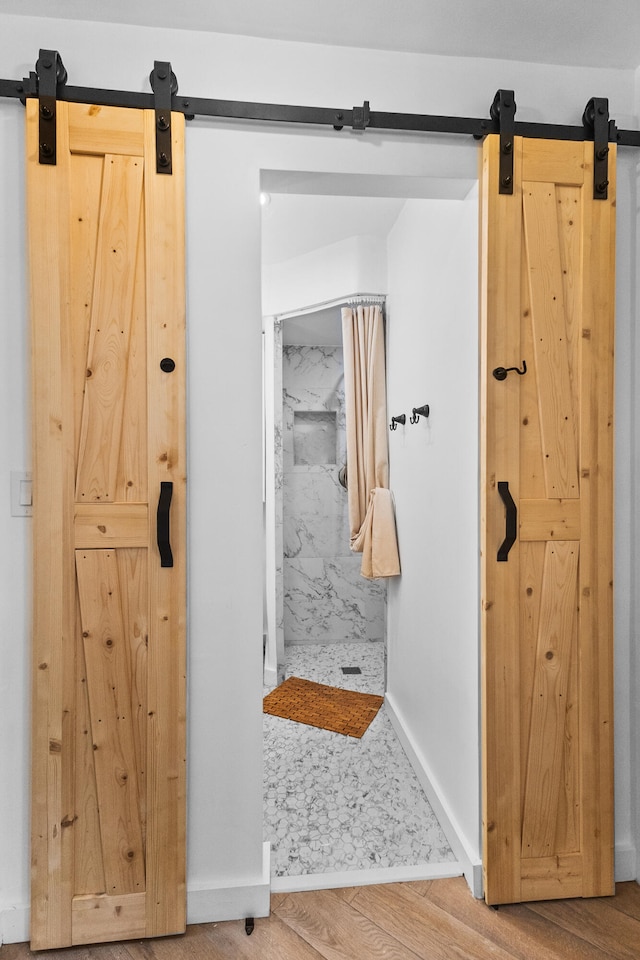 bathroom with a tile shower and hardwood / wood-style flooring