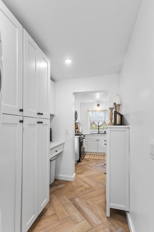 interior space with appliances with stainless steel finishes, white cabinetry, and light parquet floors